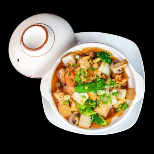 A white bowl of China Wok's Chinese stir-fry with chicken, vegetables, and mushrooms, with a lid beside it.
